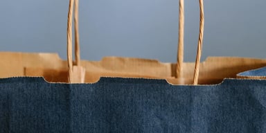 Tunna handtag på en blå papperspåse som verkar tom.