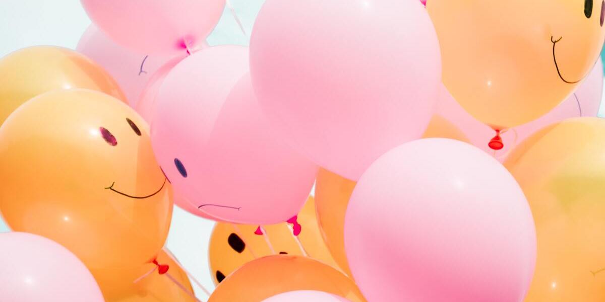 Glada och ledsna ballonger i färgerna rosa och gult.
