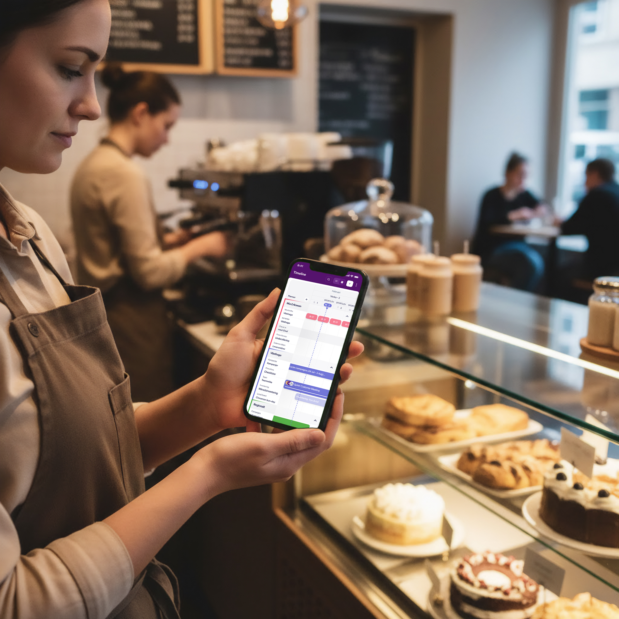 Kafémedarbetare läser i mobilen bakom disken
